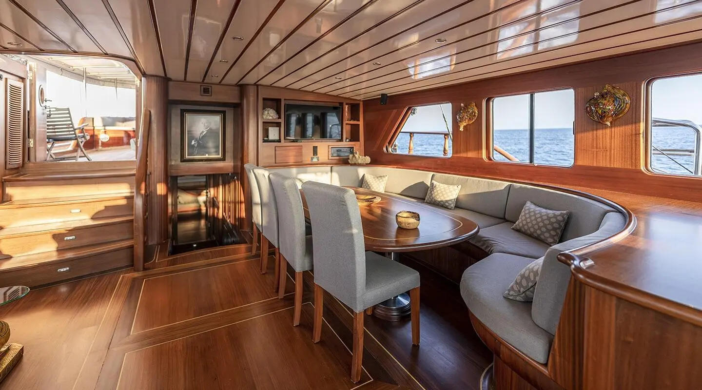 Interior dining area on a yacht with wooden floors and cushioned seating