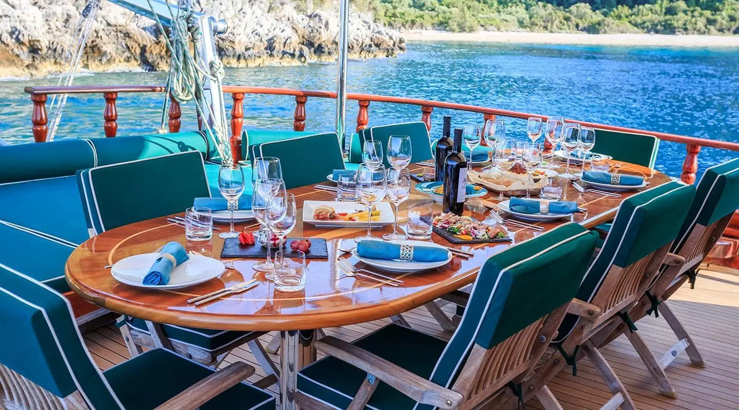 Table set for dining on a yacht deck with blue water in background
