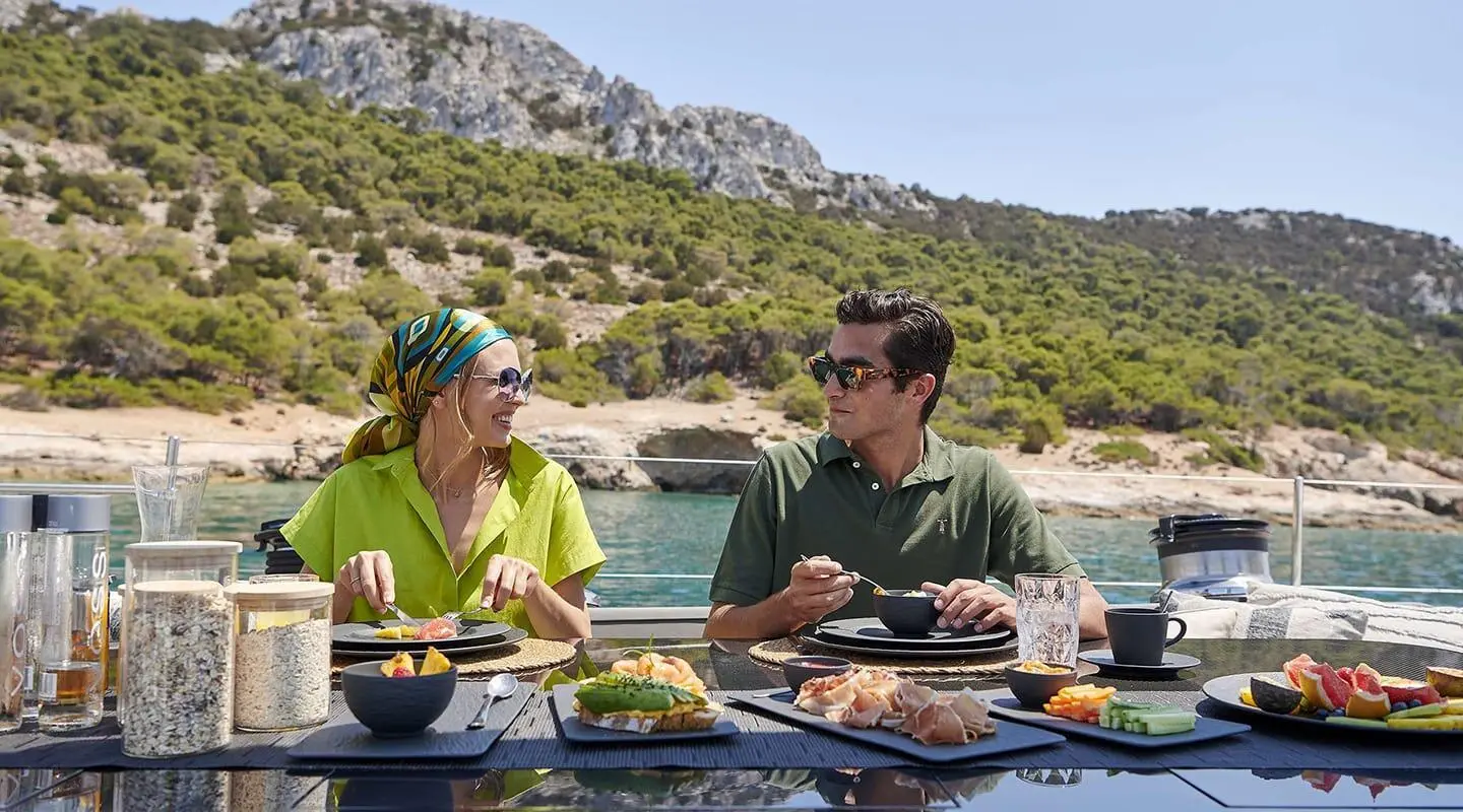 Yacht Aizu passengers enjoy meals on deck with rocky coastal backdrop