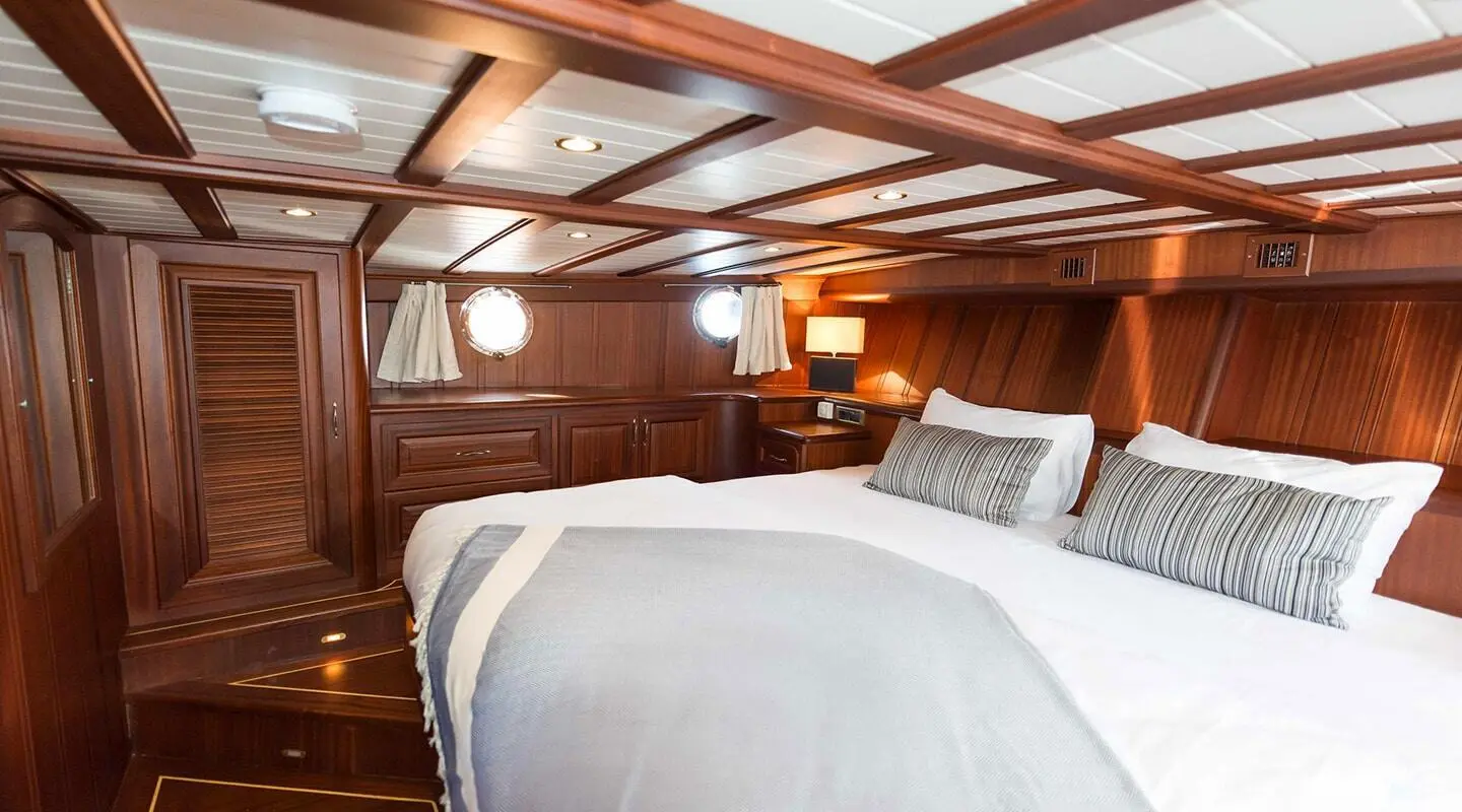 Wooden yacht cabin with a large bed and striped pillows