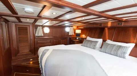 Wooden yacht cabin with a large bed and striped pillows