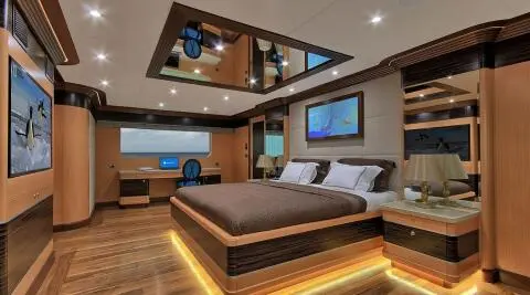 Meira yacht cabin interior with bed, seating area, wood accents, LED lighting