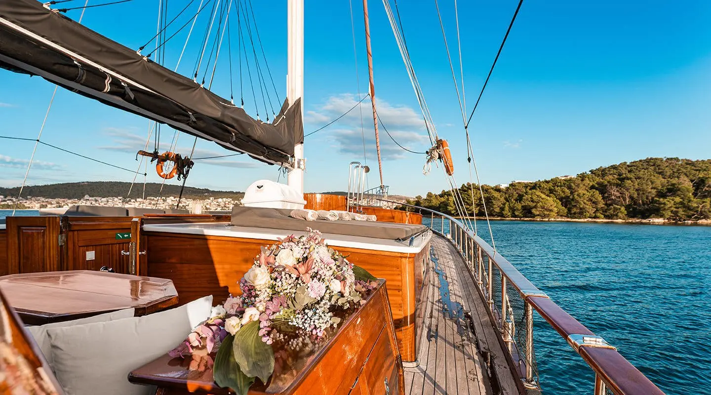 Sun deck on a Croatia gulet with wooden railings and flowers, blue sea