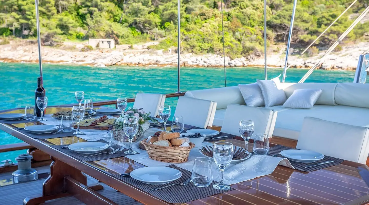Andi Star gulet at sea with dinner table, sunset and coastline