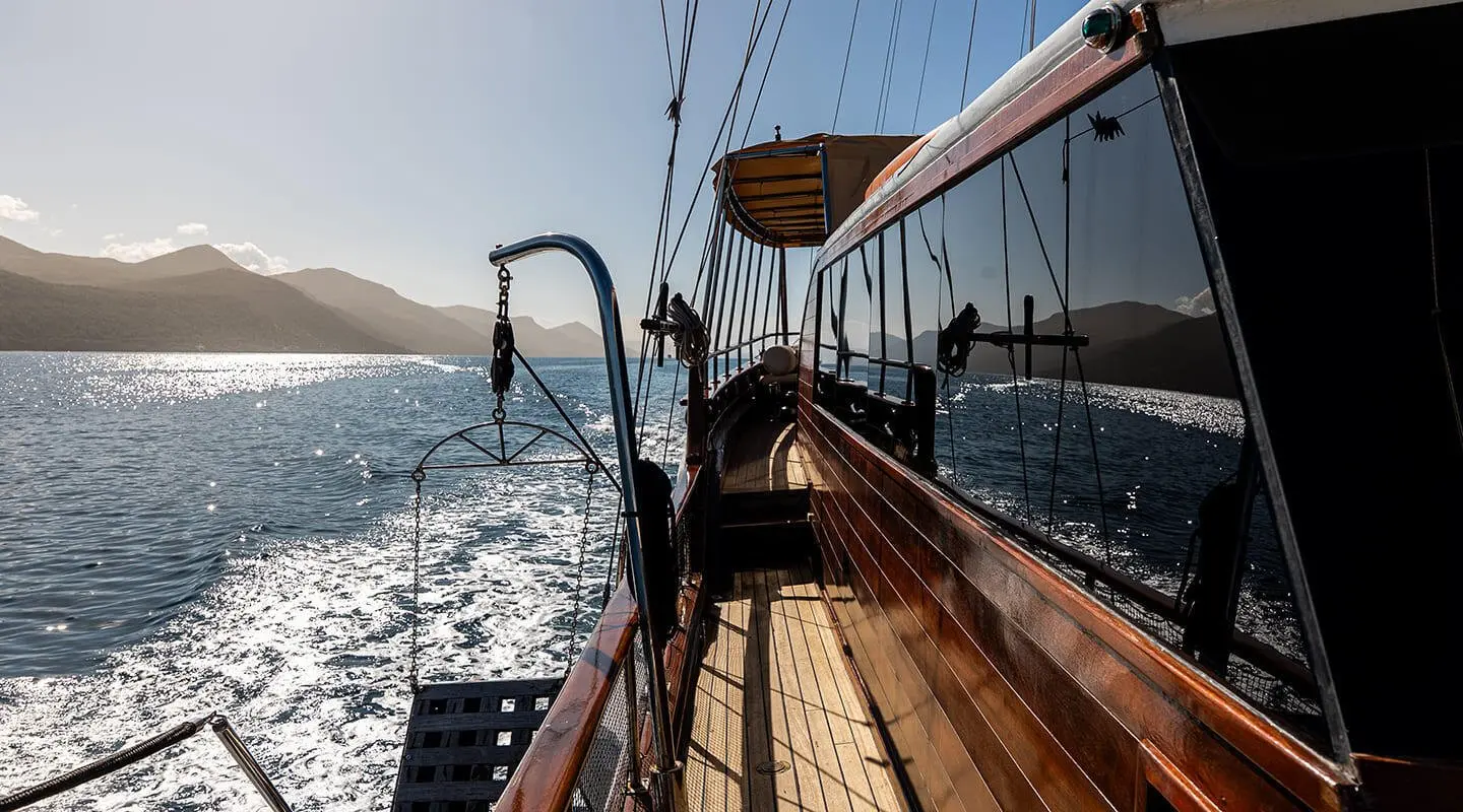 Sunset view from Eleganza yacht deck with polished wood planks and rigging