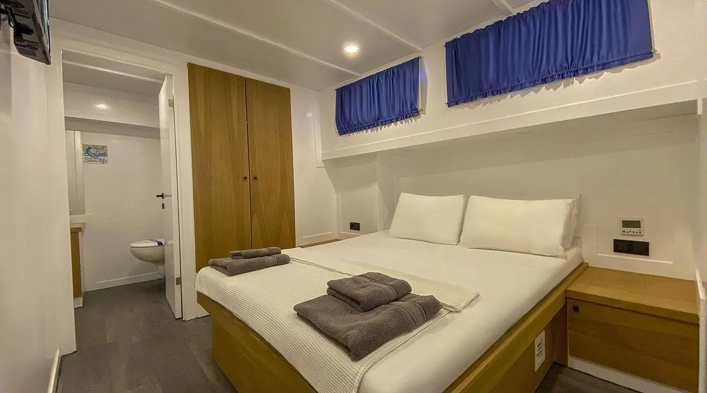 Maske 5 yacht cabin interior with two single beds and blue window valances