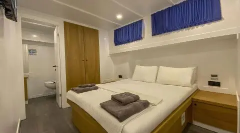 Maske 5 yacht cabin interior with two single beds and blue window valances