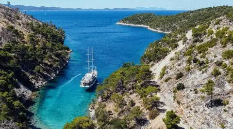 A 48m gulet yacht moored in a narrow rocky canyon with clear blue water