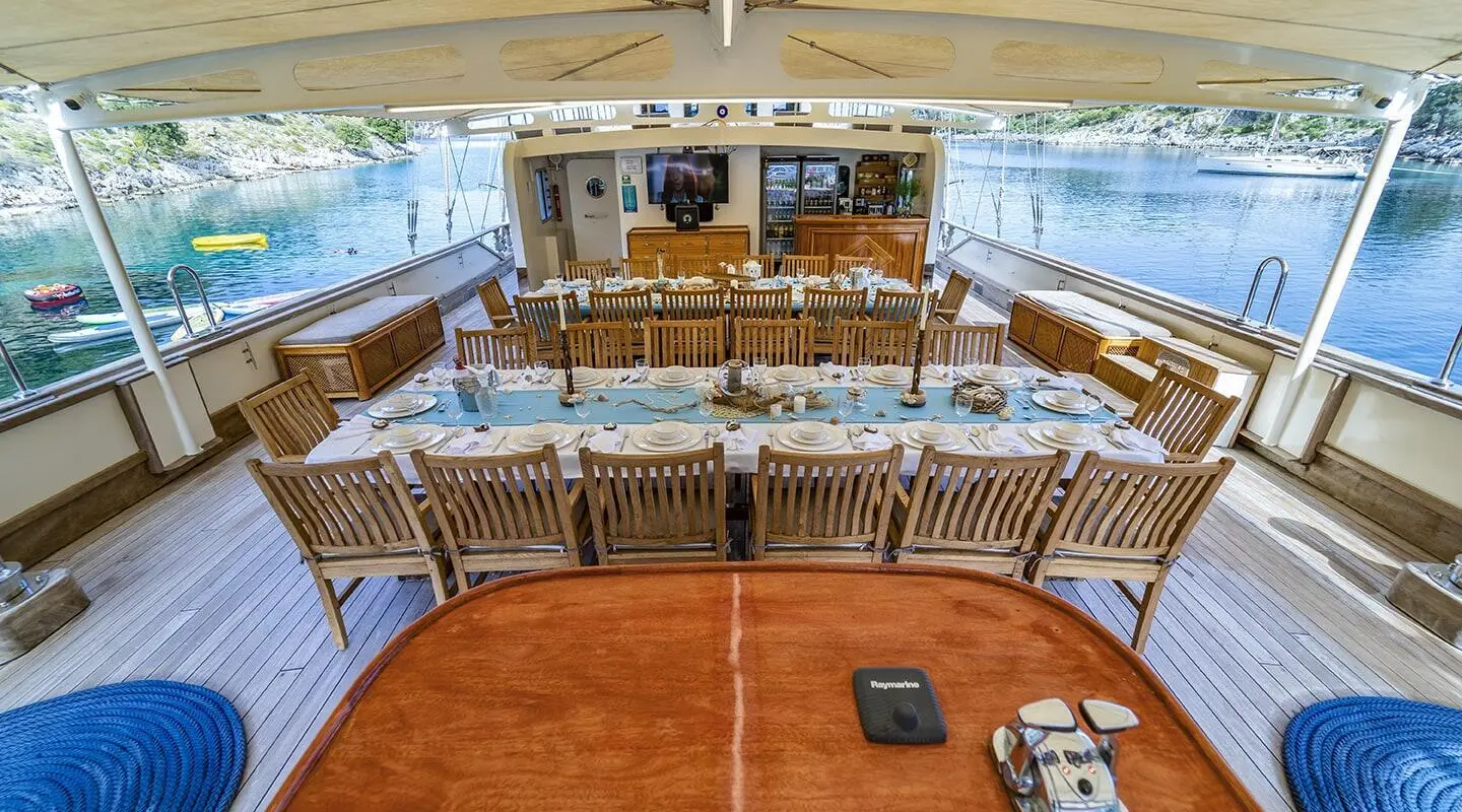 Tersane 8 yacht deck dining area with wooden chairs facing aft sunset sails