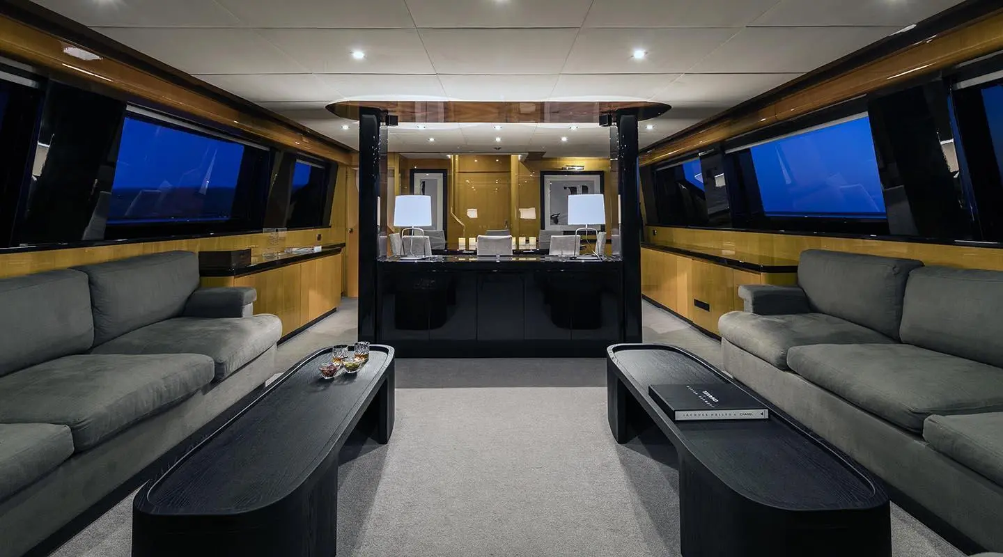 Interior of luxury yacht salon with central helm, seating area, and warm lighting