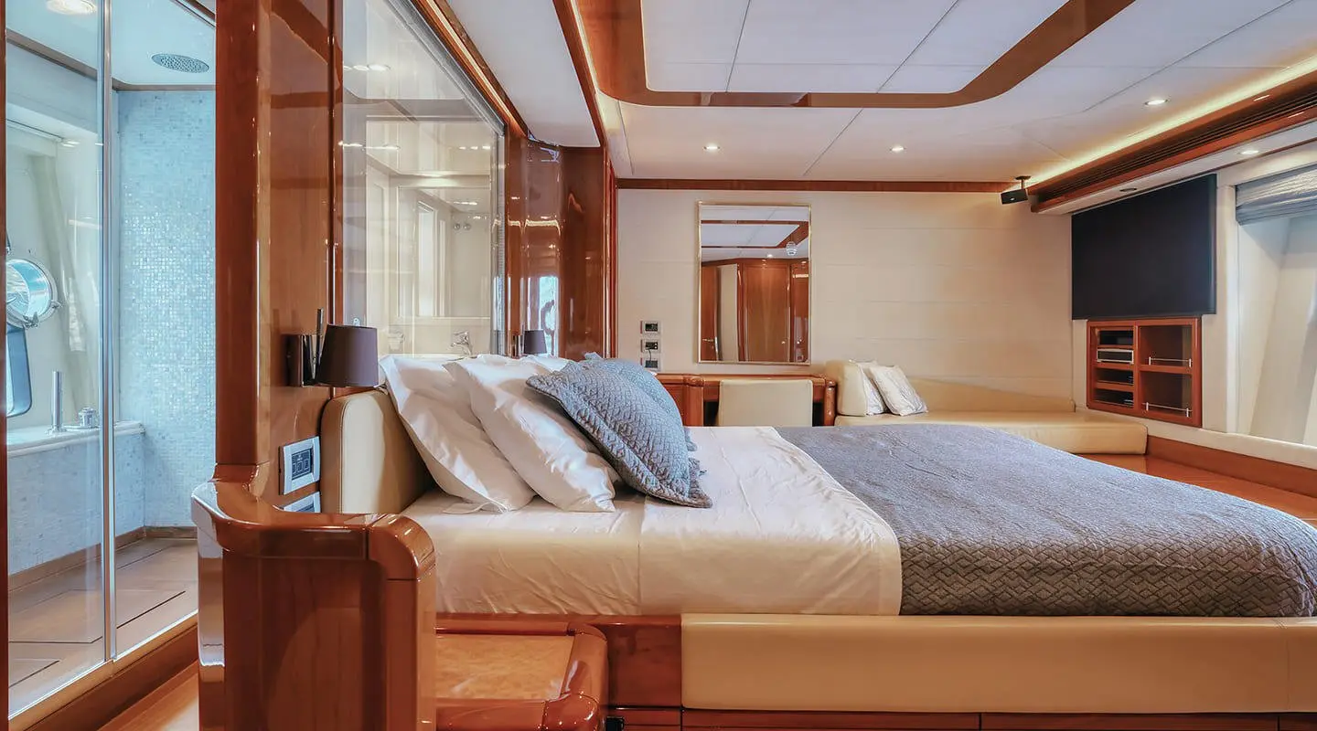 Lydia yacht's double cabin interior with bed, pillows, wooden panels, and soft lighting