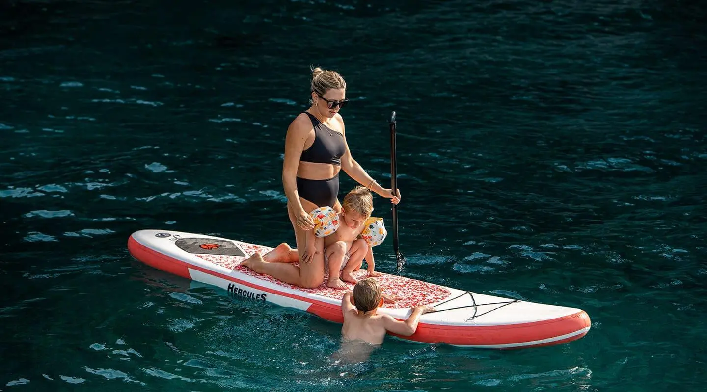 Dalmatino yacht with two people on a small red-and-white inflatable dinghy in blue water