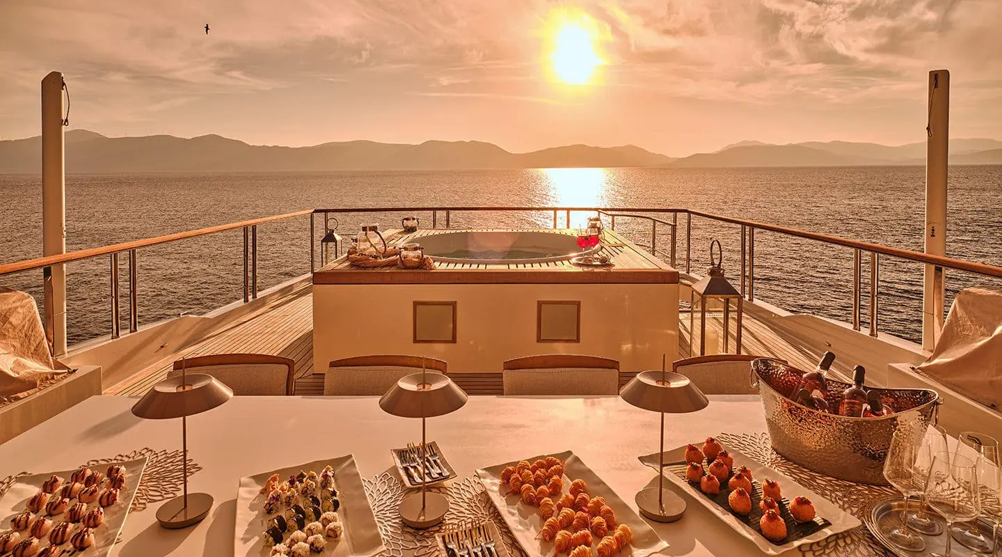 La Pellegrina 1 luxury yacht deck at sunset with dining setup and ocean backdrop
