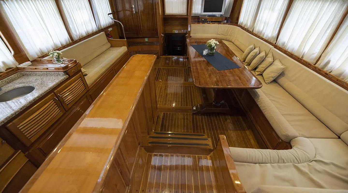 Kayhan 5 yacht interior with polished wood seating and a central table at sunset