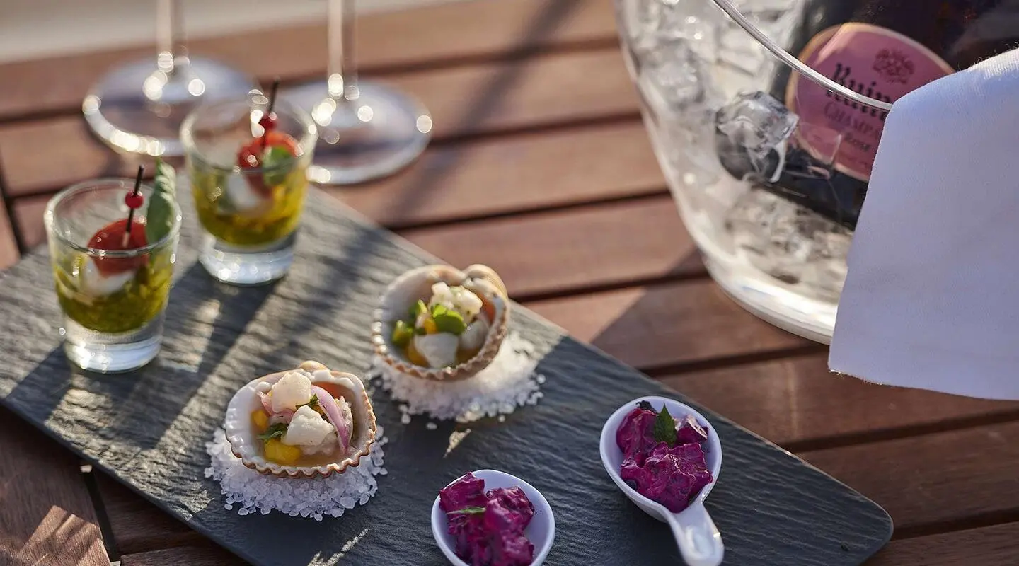 Aizu yacht on water with champagne flutes and tasting plates on deck