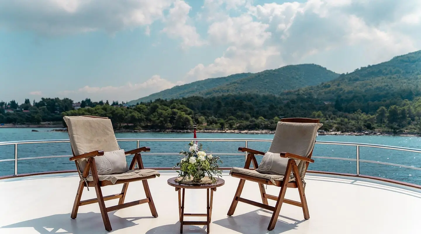 Cesarica gulet sun deck with two chairs and a small table with flower arrangement