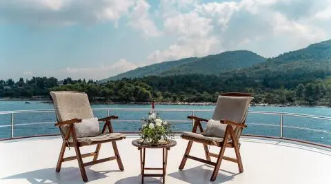 Cesarica gulet sun deck with two chairs and a small table with flower arrangement