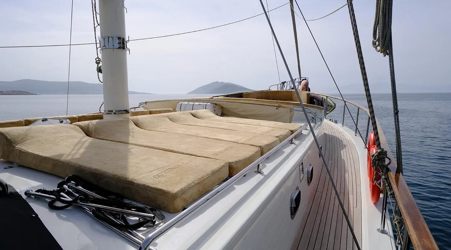Queen Of Sea yacht deck with beige cushions and rigging at sunset