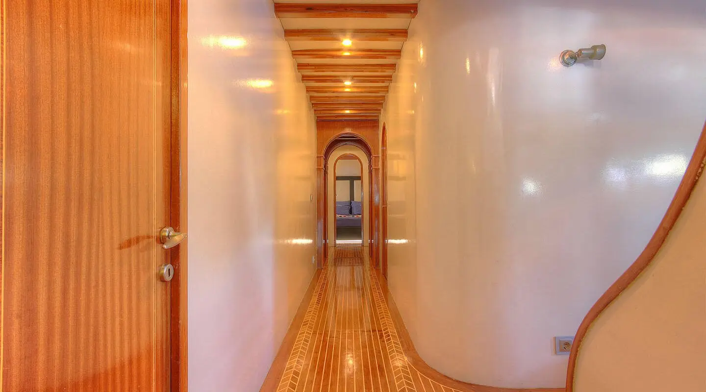 Angelo II gulet corridor with wooden floor and walls, a narrow passageway extending ahead