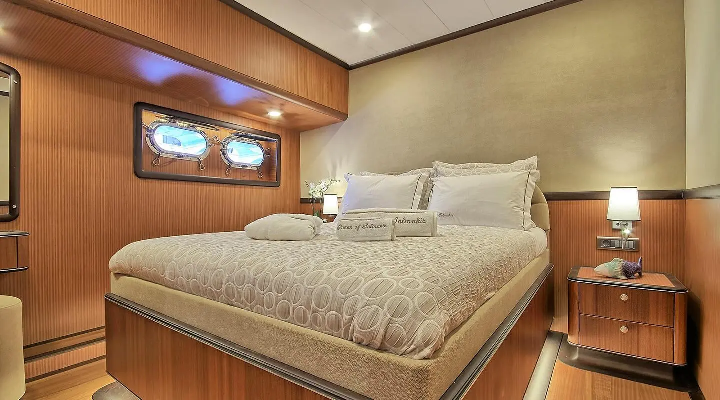 Queen Of Salmakis yacht bedroom interior with large bed and warm lighting