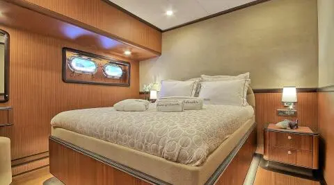Queen Of Salmakis yacht bedroom interior with large bed and warm lighting