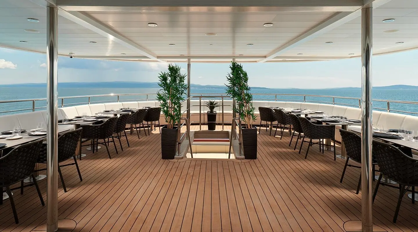 Ohana yacht dining deck with seating, tables, and ocean view under sky