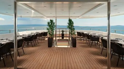 Ohana yacht dining deck with seating, tables, and ocean view under sky