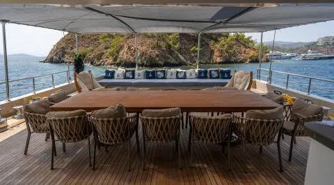 Deck scene aboard De Love yacht with teak floor, table, and chairs