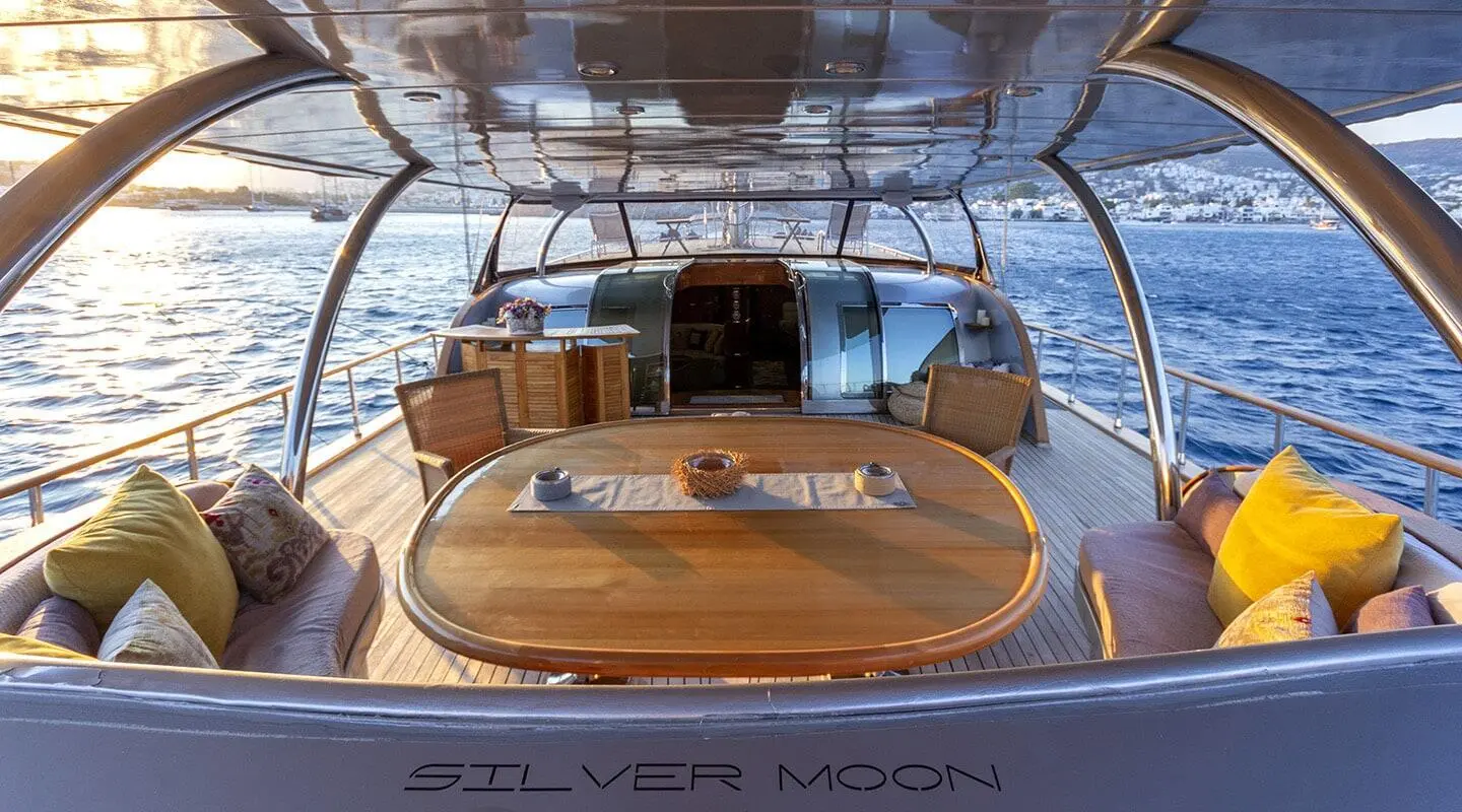 Sunlit teak deck of Silver Moon yacht with seating under shadowed canopy