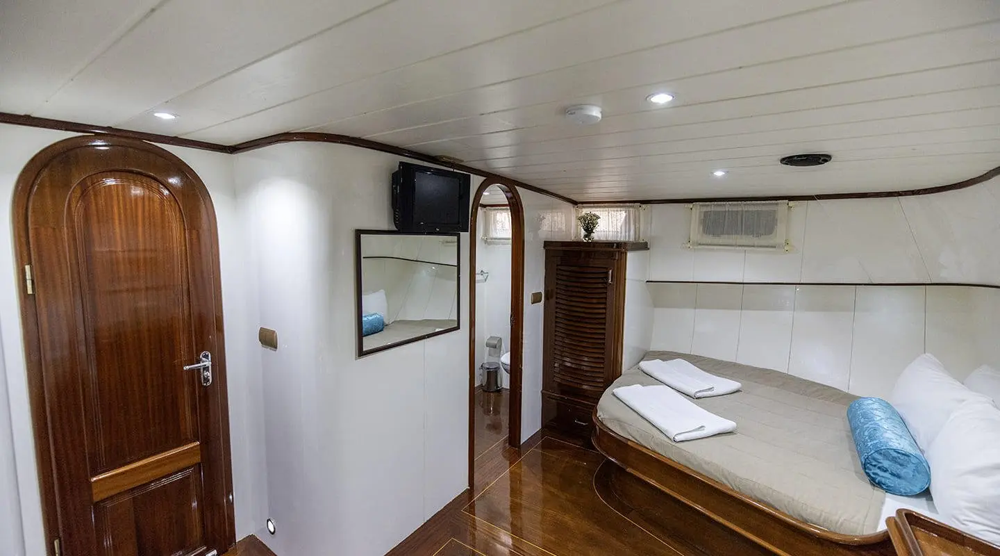 Interior of Faralya yacht with a bed, wooden floor, and white walls