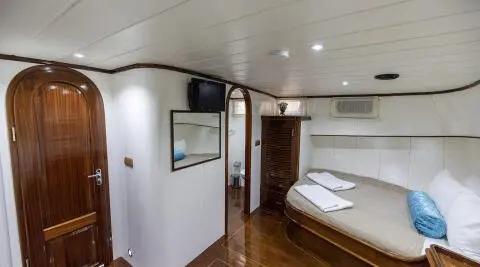 Interior of Faralya yacht with a bed, wooden floor, and white walls