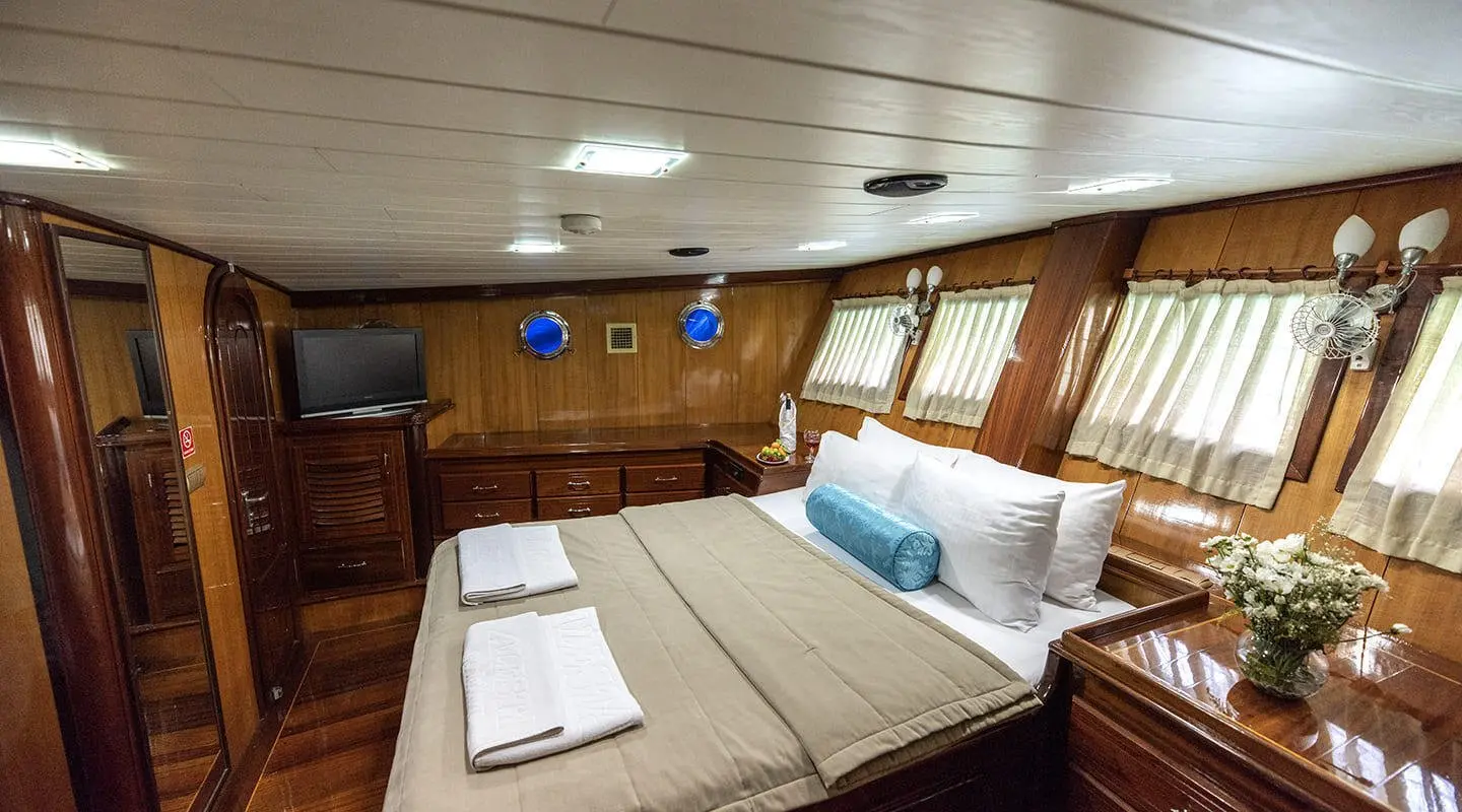 Kayhan 8 yacht charter interior: wood paneling, bed, pillows, towels, cabin lighting