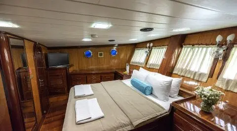 Kayhan 8 yacht charter interior: wood paneling, bed, pillows, towels, cabin lighting