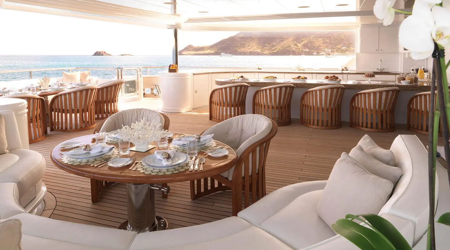 Elegant yacht dining area on Apogee with round wooden table and cushioned seating