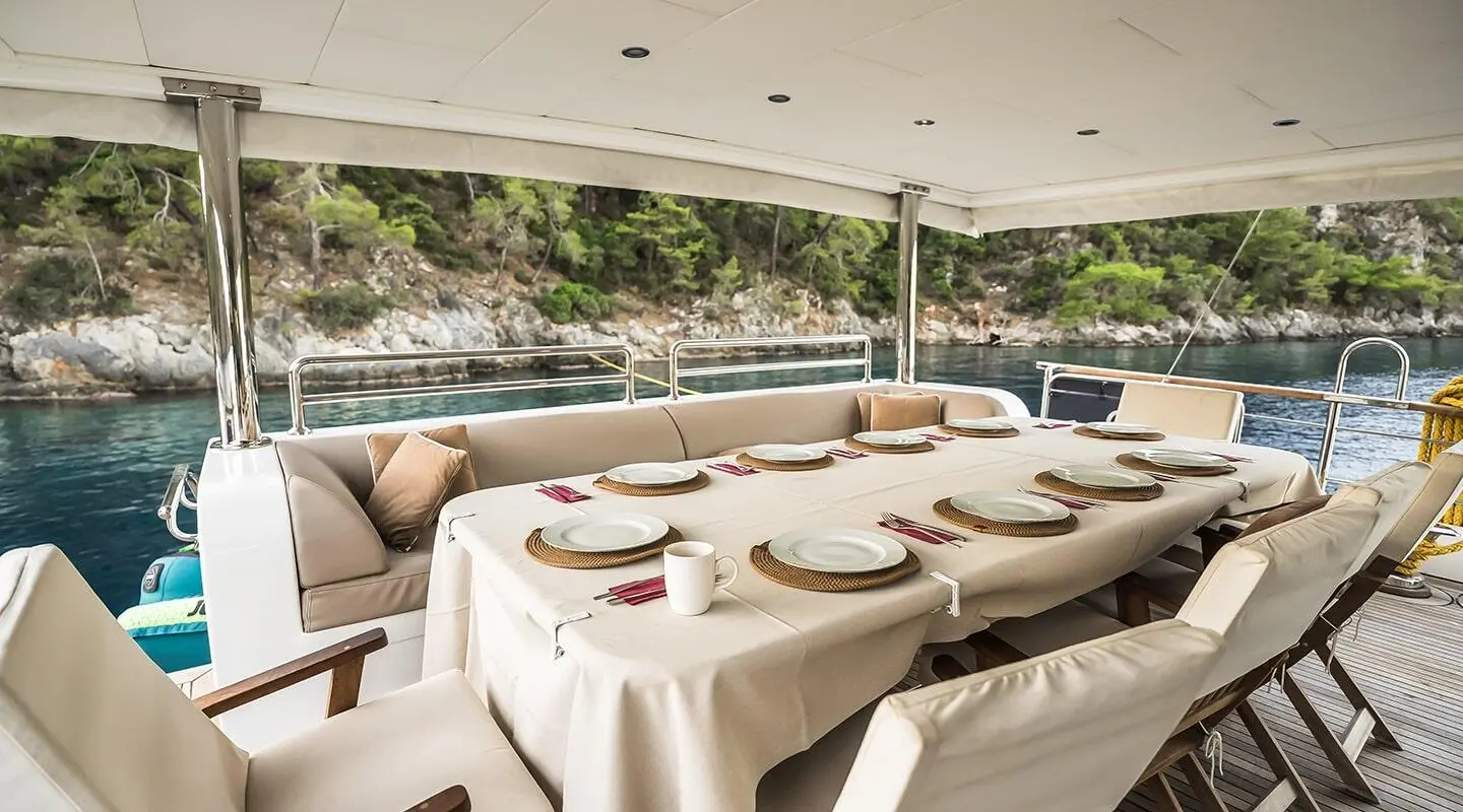 Aft deck dining setup on Belgin Sultan yacht with tableware under cover