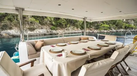 Aft deck dining setup on Belgin Sultan yacht with tableware under cover