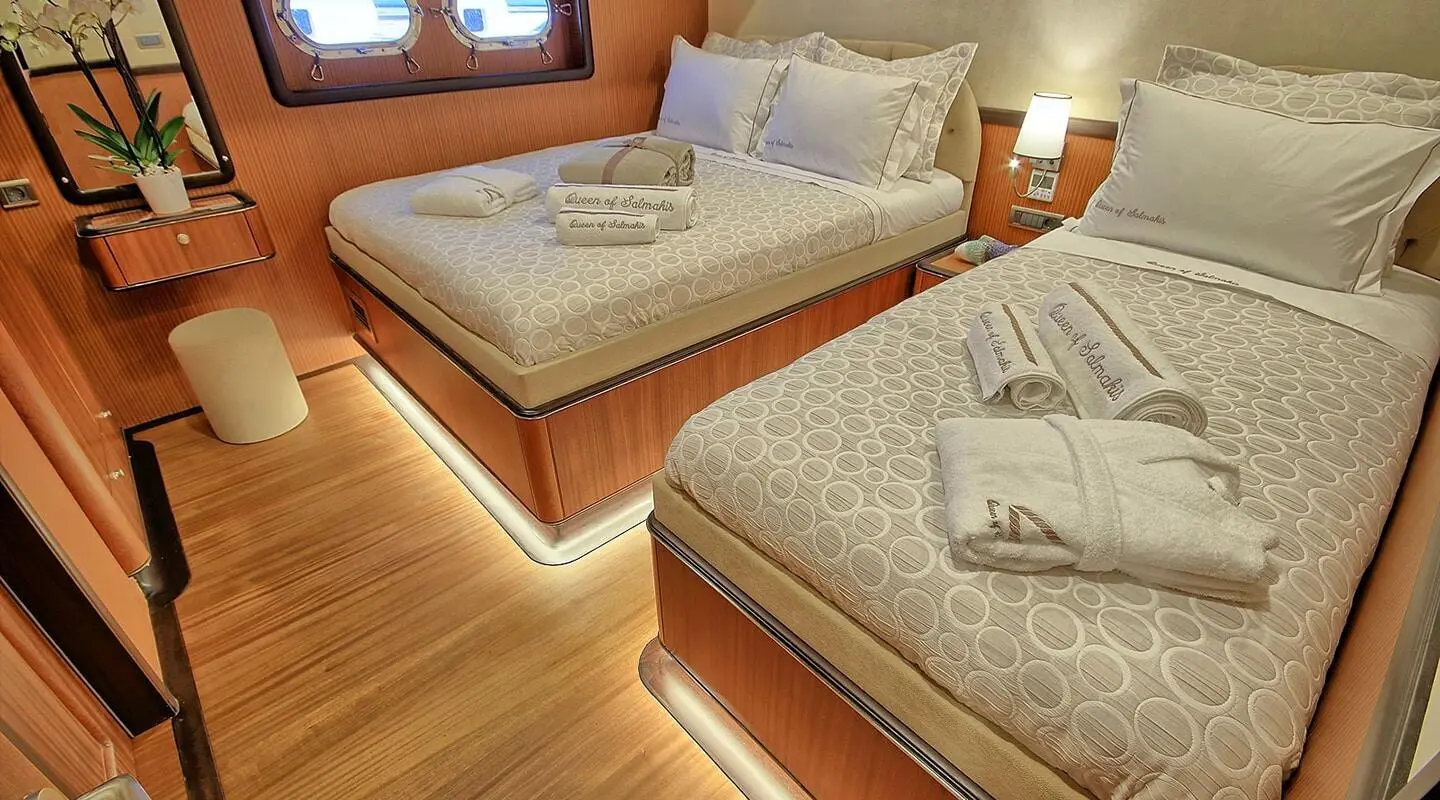 Queen Of Salmakis yacht interior with two twin beds and warm lighting