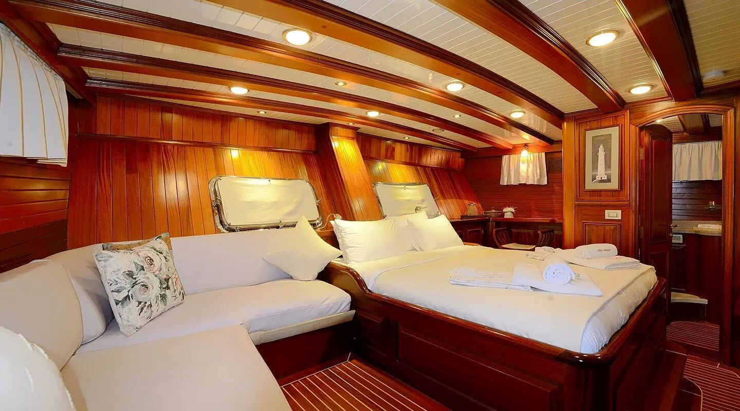 Luxurious yacht Ecce Navigo interior with plush white beds and wooden paneling
