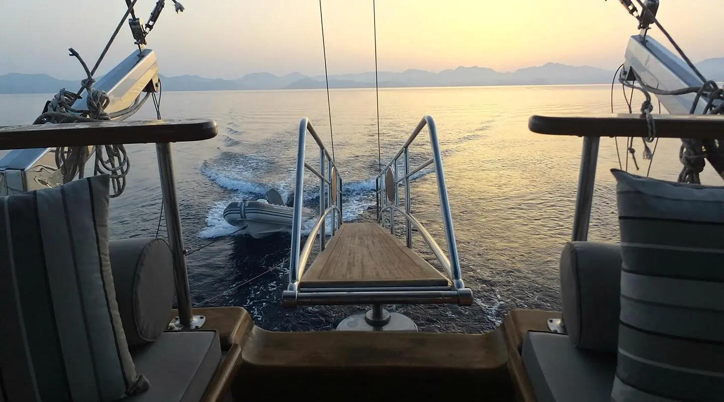 View from aft midship onto a luxury gulet yacht deck at sunset over calm waters