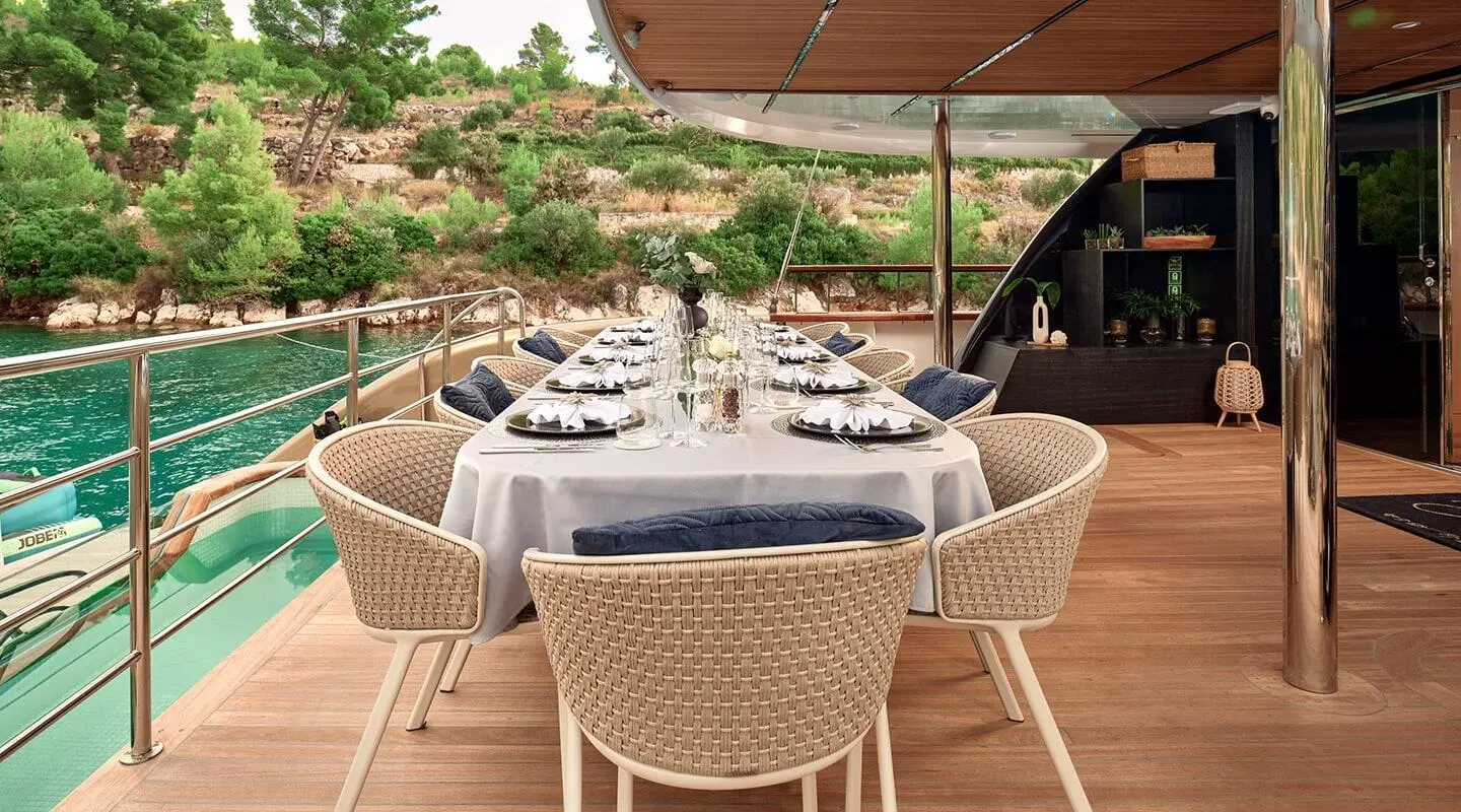 Anetta yacht dining area on deck at sunset with white wicker chairs and table