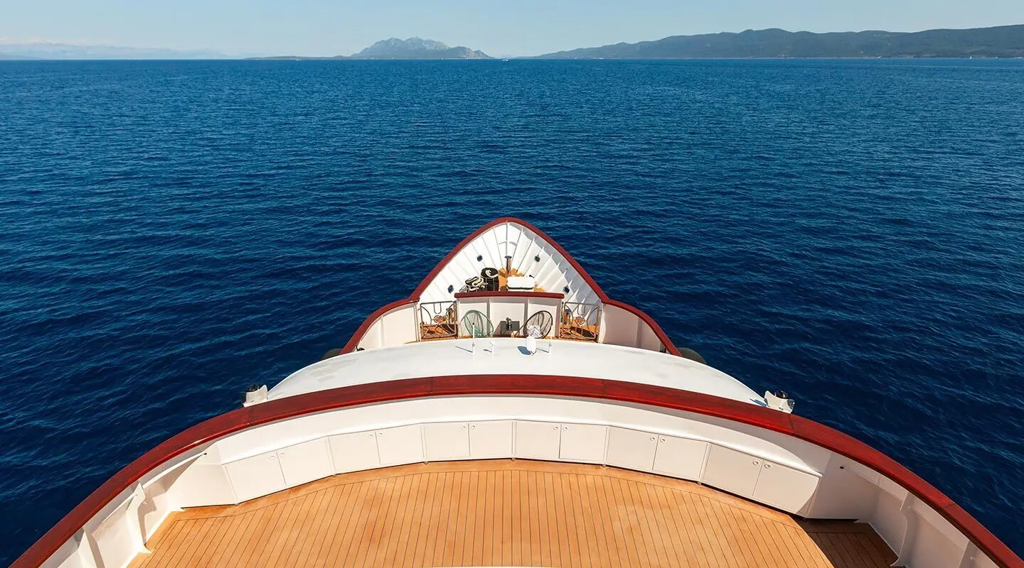 Top view of the yacht bow cutting through blue sea with a white deck edge