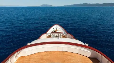 Top view of the yacht bow cutting through blue sea with a white deck edge
