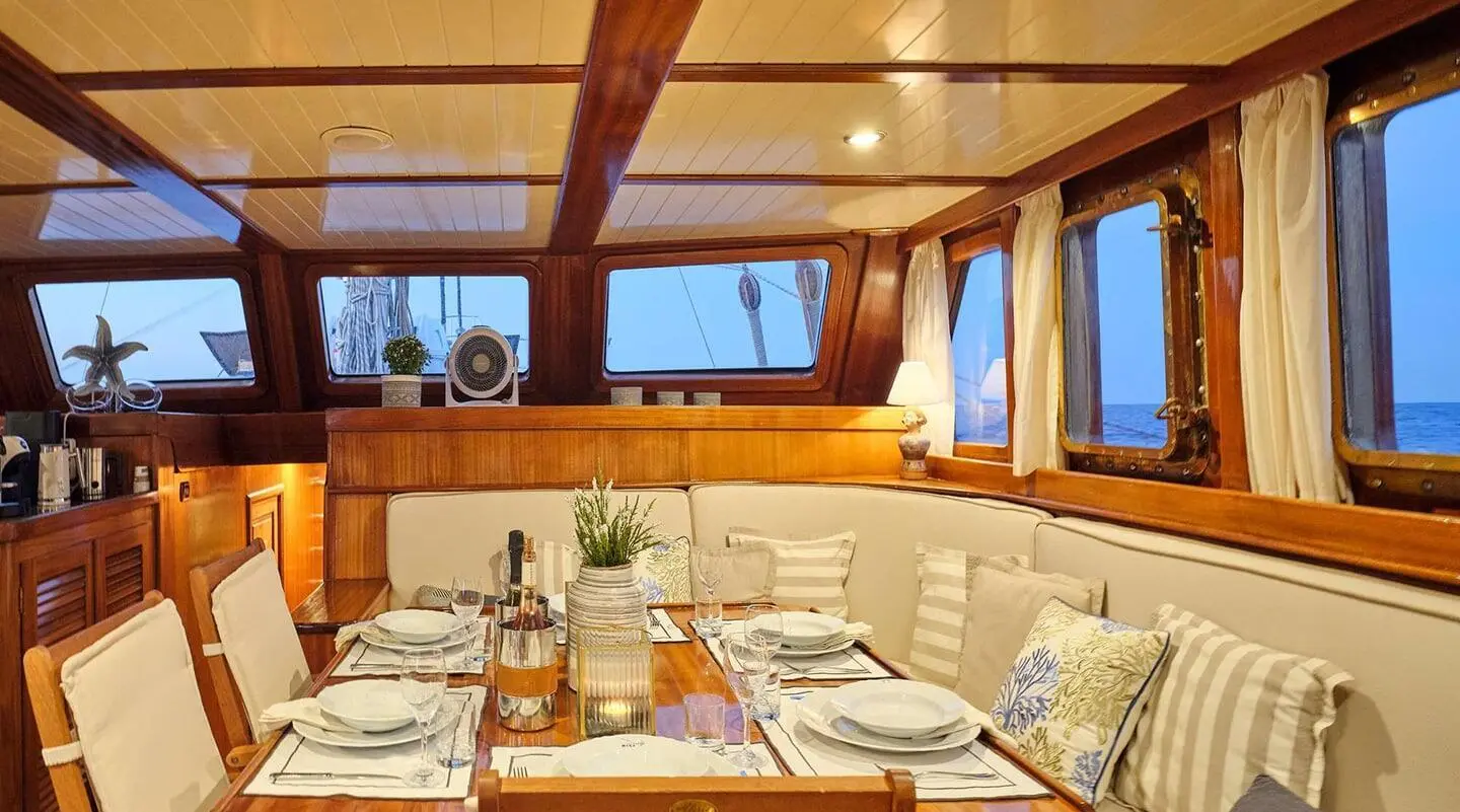 Myra yacht dining area on deck bathed in warm sunset light, tables set