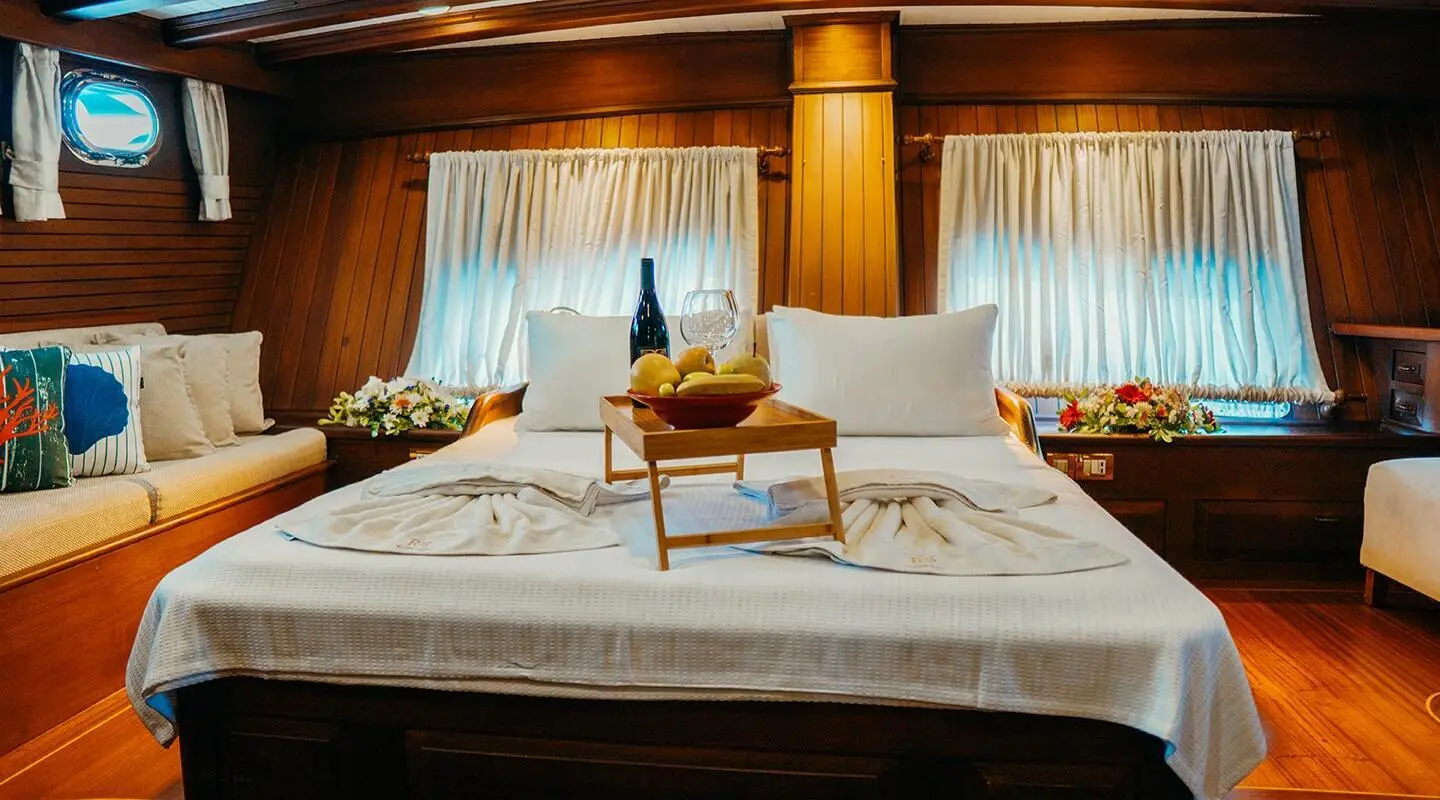 Master cabin on Wicked Felina yacht with bed, curtains, and seating area
