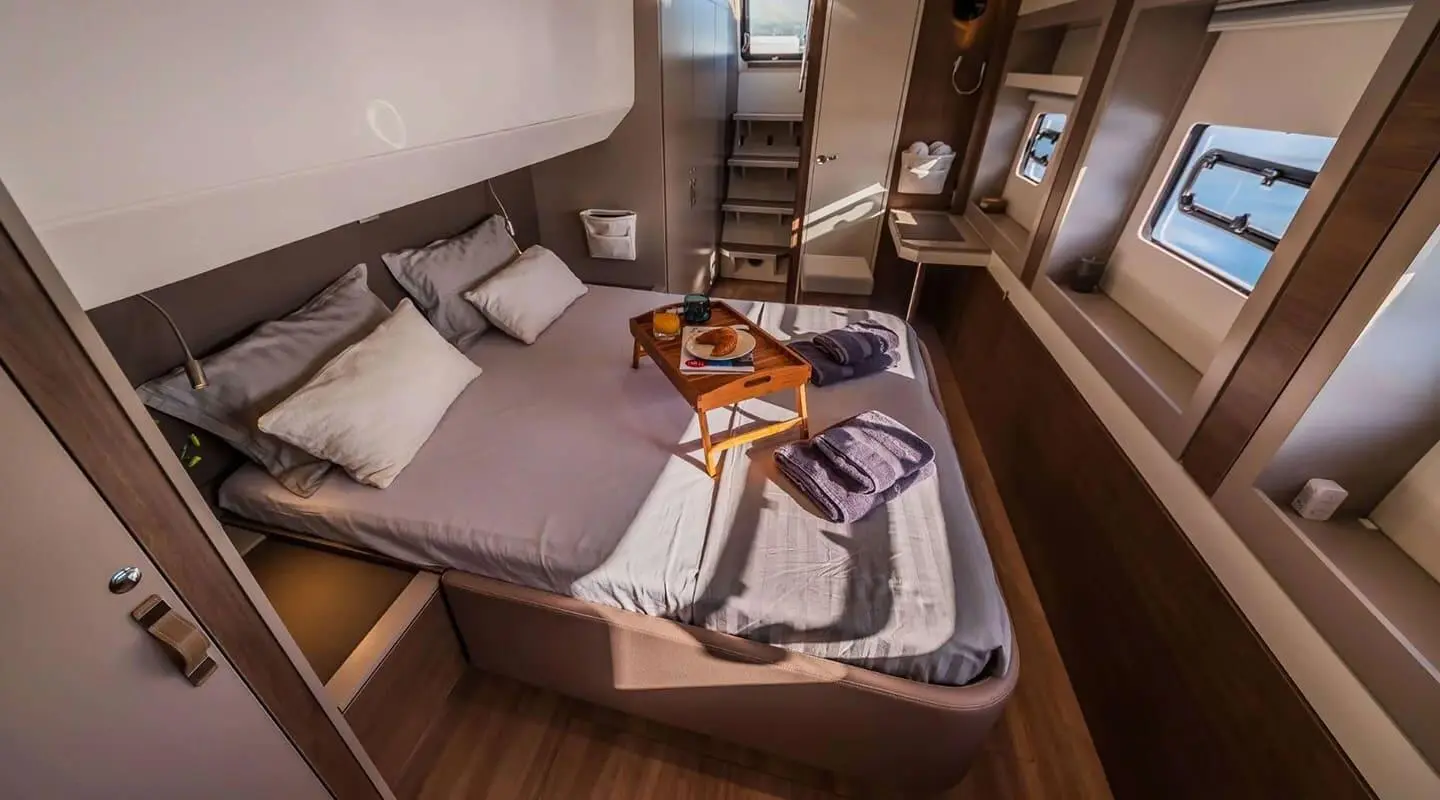 Ocean Lounge yacht interior: cabin with bed, pillows, wooden accents, and cabinet
