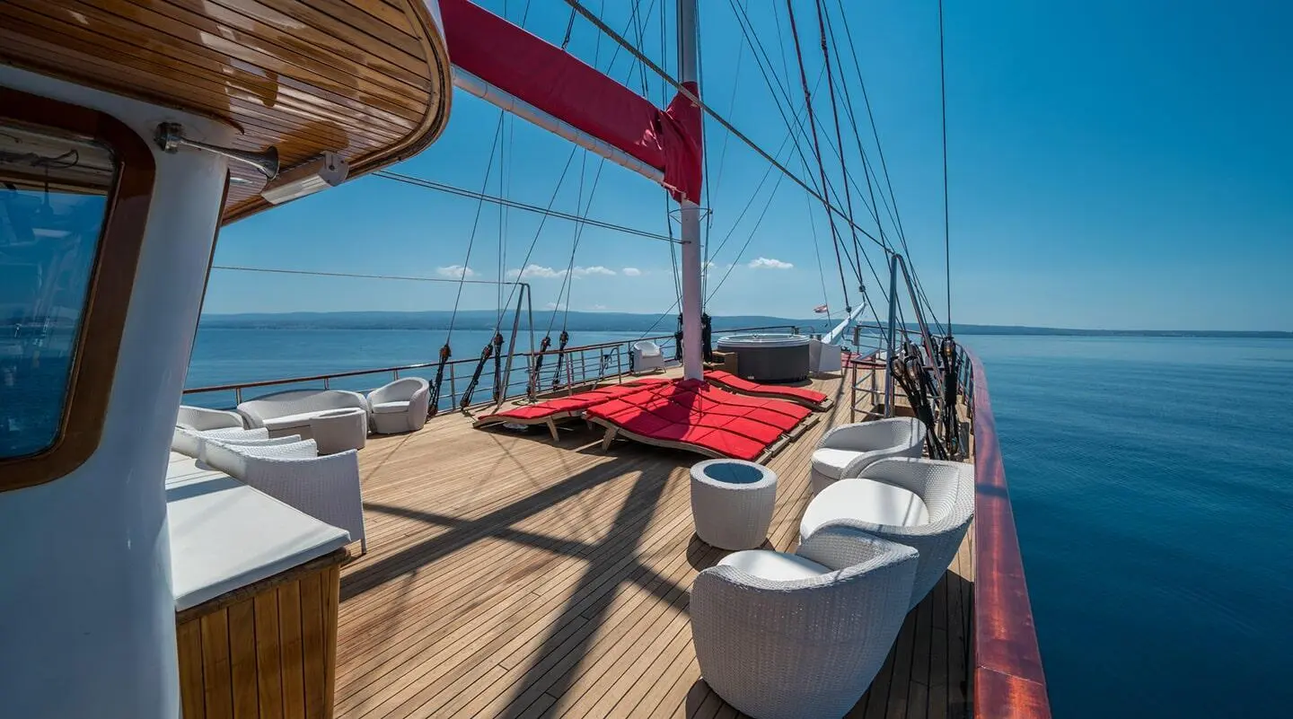 Barbara yacht bow deck with wooden planks, red lifebuoy, and white seating