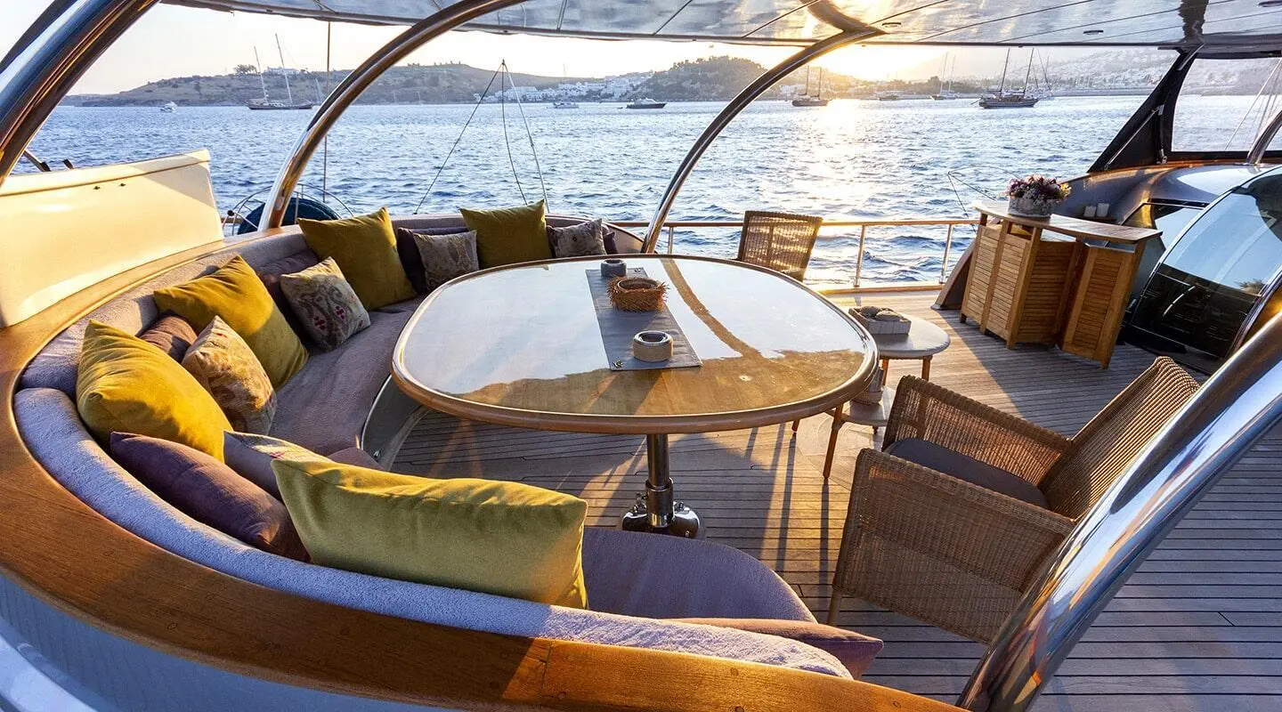 Sapphire-hulled luxury gulet at sunset with wooden deck seating and table