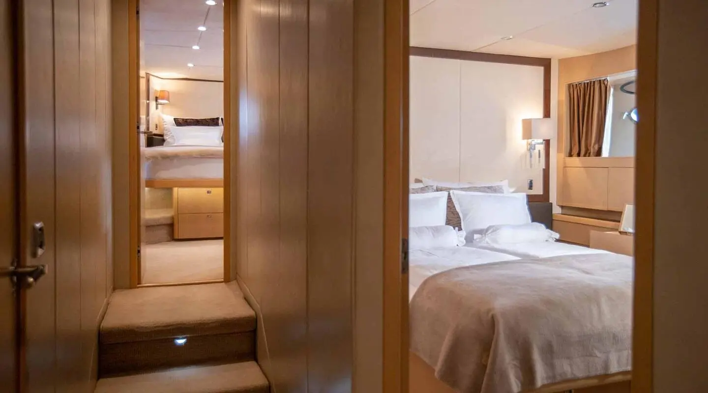 Interior hallway on Insieme yacht leading to a bedroom with bed and nightstands