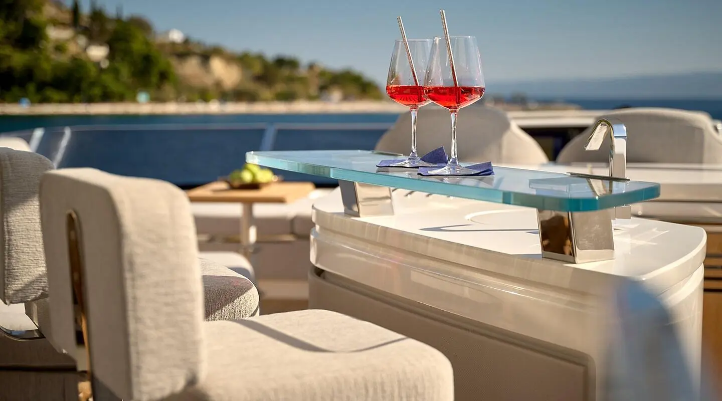 Luxurious yacht deck with sun loungers, beige seating, and blue water view at sunset
