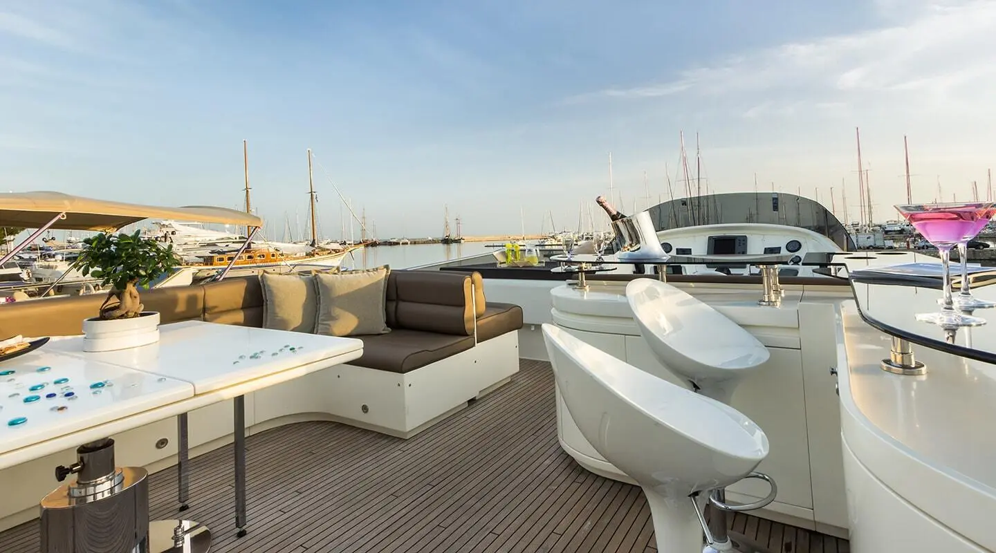 Sunlit marina deck of Amoraki yacht with seating and calm water